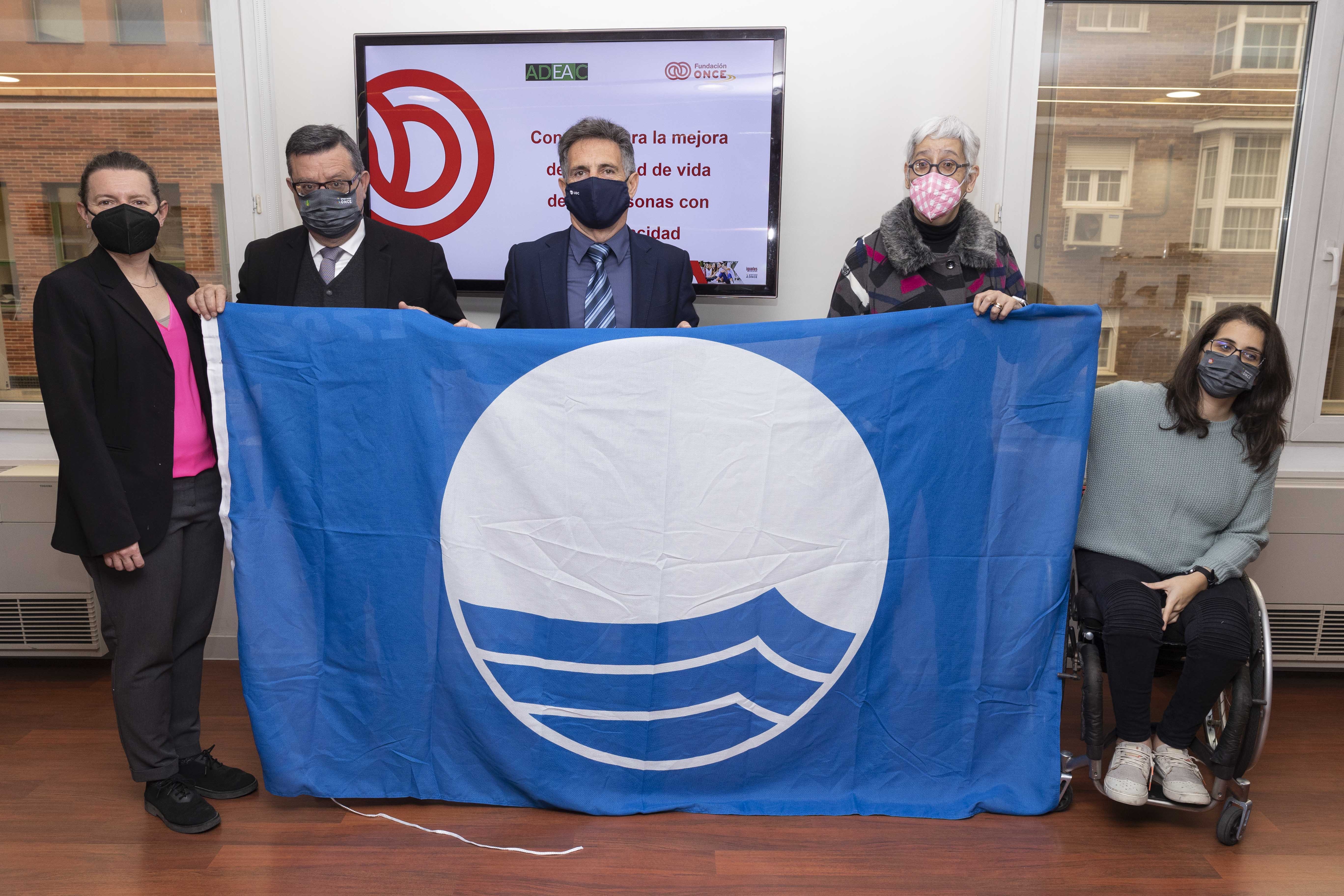 Fotografía de los firmantes con la bandera azul desplegada