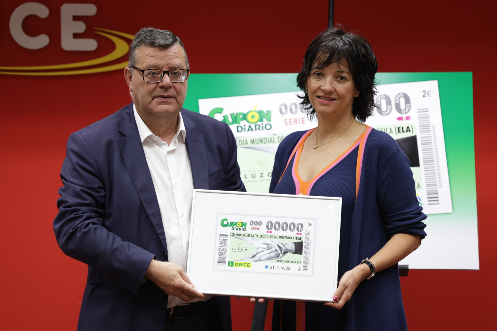 Foto de Martínez Donoso y Arregui sosteniendo la réplica del cupón en el acto de entrega en Fundación ONCE