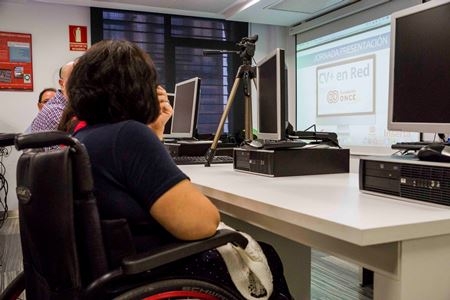 Foto de una mujer en silla de ruedas en un aula de formación
