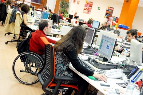 foto de un centro de trabajo en el que se ve a una persona en silla de ruedas en su puesto
