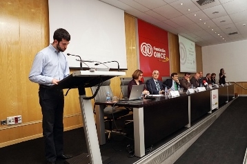 Foto de uno de los becados hablando desde el atril