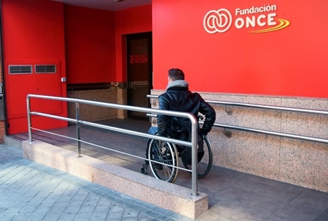 Foto de una persona en silla de ruedas entrando en la sede de Fundación ONCE
