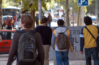 Grupo de personas caminando por una acera en una zona urbana, cerca de una universidad