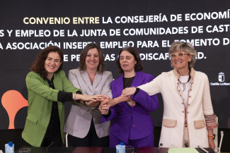 Foto de familia en la que firmantes y acompañantes tienen las manos unidas