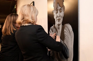 Fotografía de una de las exposiciones con una mujer tocando un cuadro
