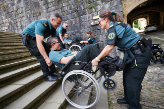 Fotografía de miembros de la Guardia Civil ayudando a una persona en silla
