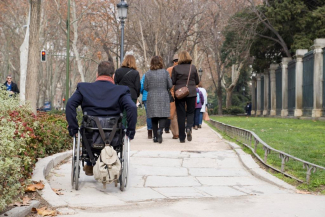 Foto de una persona en silla de ruedas paseando por una calle de Madrid