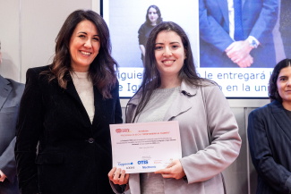 Foto de la alumna becada recogiendo el diploma