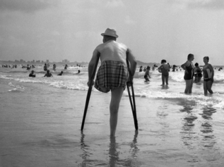 Foto Ángel Rojo, uno de los artistas con discapacidad de la Bienal de Fundación ONCE. En ella se ve a un hombre amputado de una pierna entrando al mar con muletas