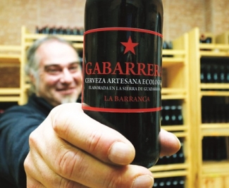 Foto de uno de los emprendedores con una botella de vino de su negocio