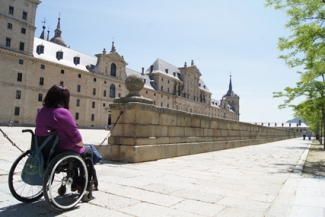 Foto de una mujer en silla de ruedas paseando por el Escorial