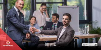 Foto de una reunión en la que dos hombre estan dándose las manos, una de ellas en silla de ruedas